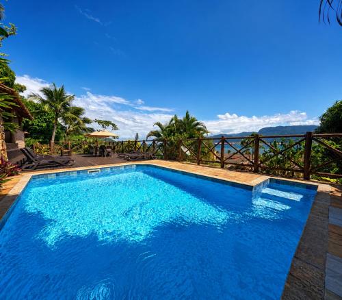 a blue swimming pool with a view of the ocean at Pousada Perequê in Ilhabela