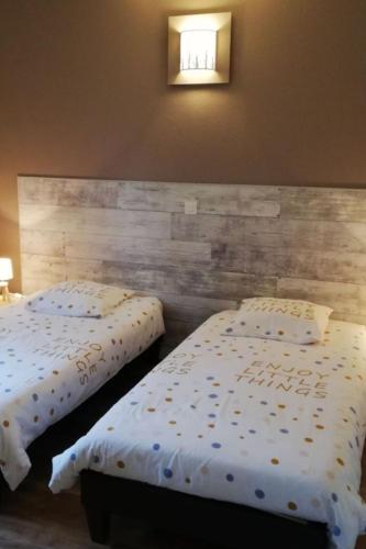 two beds in a bedroom with a wooden headboard at Le roqual in Carsac-Aillac