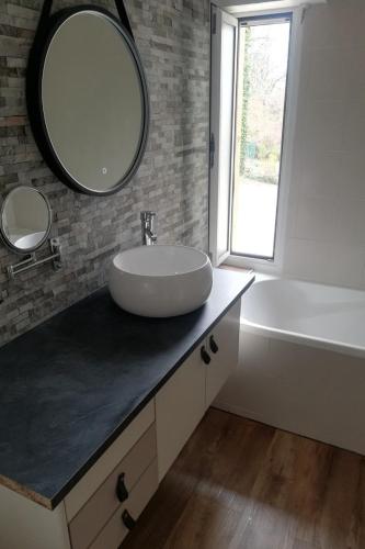 a bathroom with a sink and a tub and a mirror at Le roqual in Carsac-Aillac