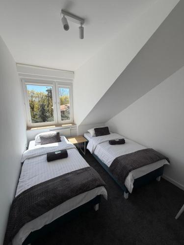 two beds in a room with a window at Pensjonat Resident in Krynica Morska