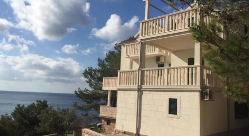 Un edificio blanco con un balcón en la parte superior. en Apartments Elvira, en Sveta Nedelja