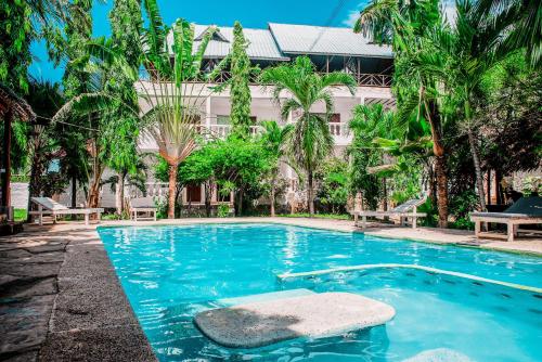 a swimming pool in front of a building with palm trees at Angie's Cozy Studio Diani Beach in Ukunda