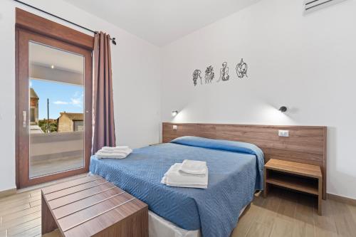 a bedroom with a blue bed and a window at CLASS ROOMS AFFITTACAMERE con bagno privato , vicino alle DUNE di PORTO PINO in SantʼAnna Arresi