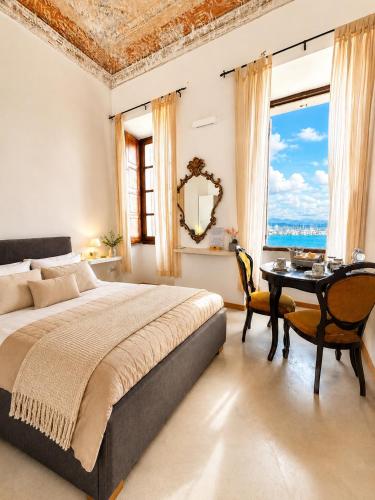 a bedroom with a bed and a table and a window at Palazzo Bolasco in Alghero