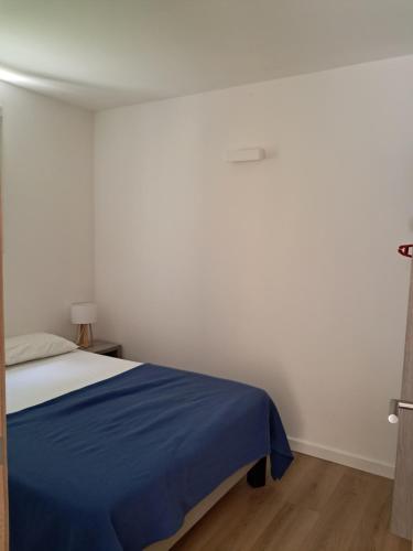 a white room with a bed with a blue blanket at Résidence de Tourisme Fior di Rena in Saint-Florent