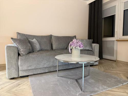 a living room with a couch and a table with flowers at Urban Relax AC Progres in Toruń