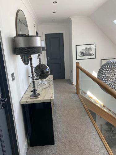 ein Flur mit einem Tisch mit einer Lampe und einer Treppe in der Unterkunft Hillvine in Hartpury