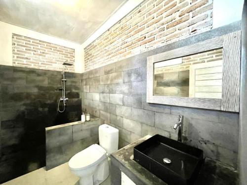 a bathroom with a white toilet and a sink at The Breezy Volcano in Kintamani