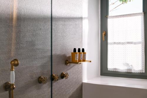 a shower with a glass door with bottles on a shelf at Patmos Eye Boutique Hotel & Villas in Skala