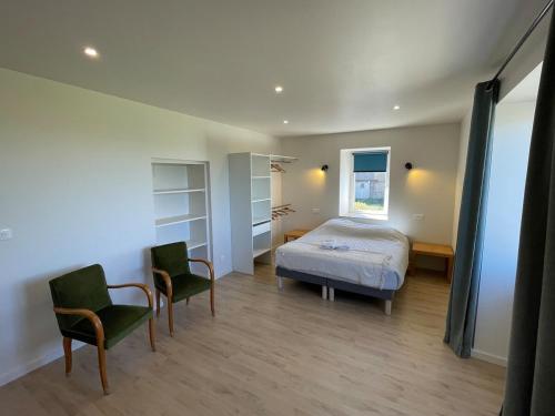 a bedroom with a bed and two chairs at La ferme Bourguignonne in Saizy