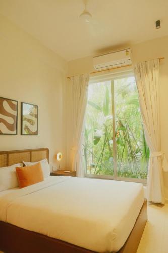 a bedroom with a bed and a large window at Aura Stays L8 in Vagator