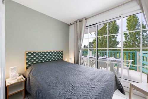 a bedroom with a bed and a large window at La Terrasse du Golf Bourgenay in Talmont