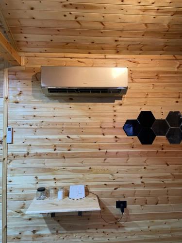 ein Zimmer mit einer Holzwand und einer Lampe in der Unterkunft Cherry farm in Adschlun