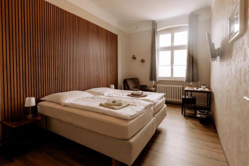 a bedroom with a bed and a desk and a window at Hotel Ratsstuben Kalbe in Kalbe