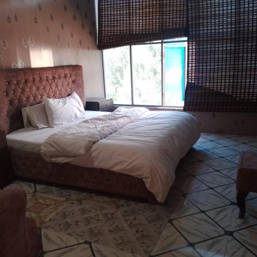 ein großes Bett in einem Schlafzimmer mit einem großen Fenster in der Unterkunft River Breeze Hotel in Mingora