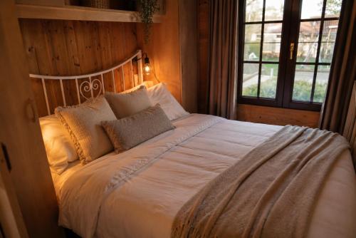 a bedroom with a bed with white sheets and pillows at Rustig Chalet Ardennen The Forest Haven in Amblève