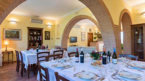 a restaurant with white tables and chairs with wine bottles at PODERINA DEI POGGI 12, Emma Villas in Castiglione del Lago