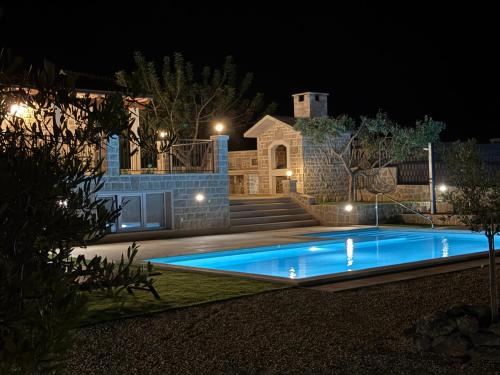 a swimming pool in a yard at night at Villa Maginja in Sutivan