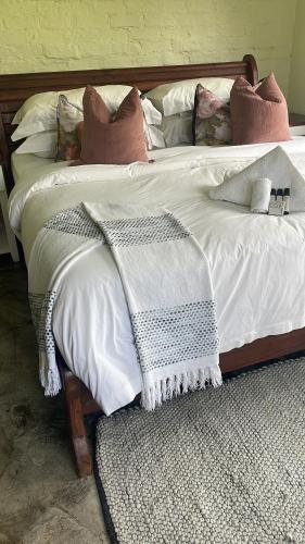 a white bed with pillows and a blanket on it at Indaba tree lodge in Bulawayo