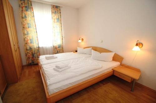 a bedroom with a bed with white sheets and a window at Ferienwohnung Feuerstein in Sassnitz