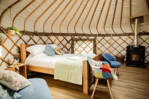 a room with a bed and a chair in a yurt at Kelburn Yurts - Cockle in Fairlie