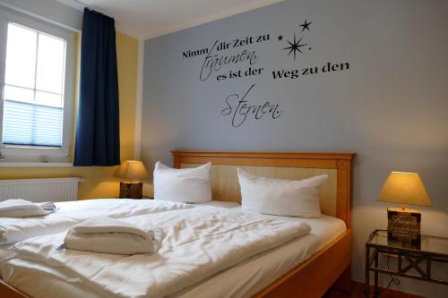 a bedroom with a bed with white sheets and words on the wall at Ferienwohnung Kranichglück in Neddesitz