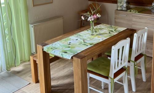 a dining room table with a vase of flowers on it at Ferienwohnung Stockrose in Lohme