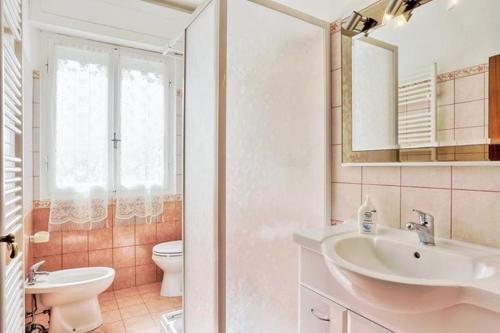 a bathroom with a sink and a toilet and a mirror at Villaedi in Marina di Bibbona