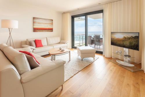 a living room with a white couch and a large window at Villa Friede-Marie App Freya in Sassnitz
