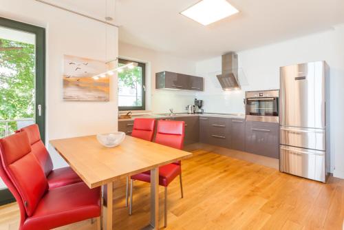 a kitchen with a wooden table and red chairs at Villa Friede-Marie App Freya in Sassnitz