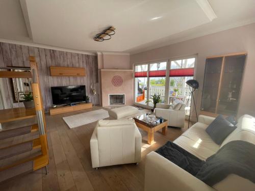 a living room with a white couch and a tv at Villa Seestern - Ferienhaus mit Meerblick in Sassnitz