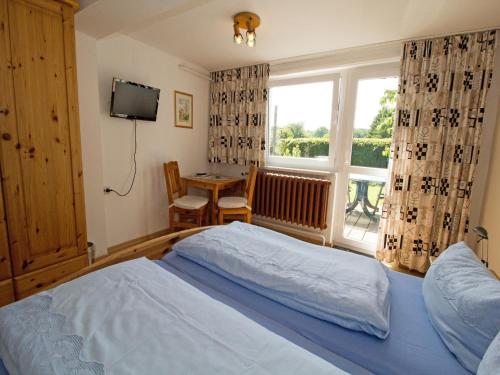 a bedroom with a bed and a table and a window at Ferienzimmer zum Försterberg in Hagen