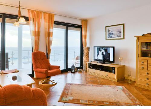 a living room with a television and a couch and chair at Villa Friede-Marie, FeWo Meeresidyll in Sassnitz