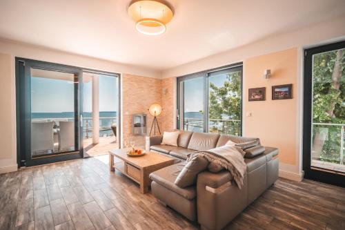 a living room with a couch and large windows at Villa Friede Marie FeWo Ostseeweitblick in Sassnitz