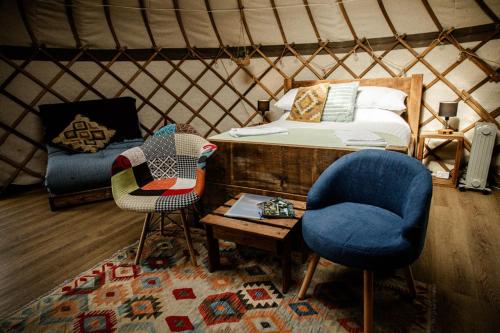 a yurt with two chairs and a bed and a table at Kelburn Yurts - Fechan in Fairlie