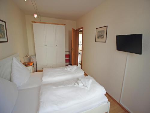 two white beds in a room with a television at Villa Seeblick - Apartment 309 in Sassnitz