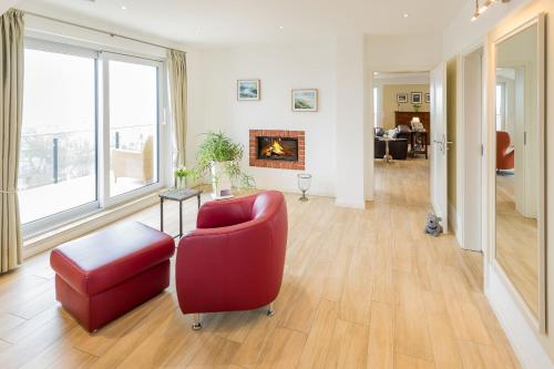 a living room with a red chair and a fireplace at Villa am Kreidebruch - Ostseeweitblick in Sassnitz