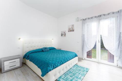 a white bedroom with a bed and a window at Casa della Luna con piscina in Budoni