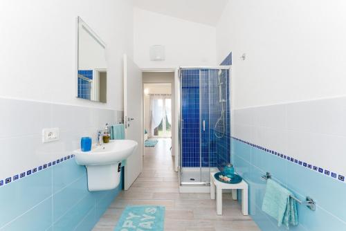 a blue and white bathroom with a sink and a shower at Casa della Luna con piscina in Budoni