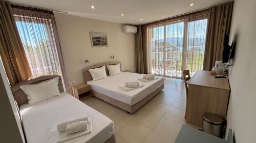 a hotel room with two beds and a balcony at Семеен хотел Сирена in Ahtopol