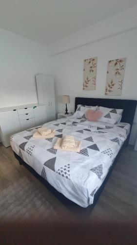 a bedroom with a large bed with black and white sheets at Aqua Lux Apartman in Jagodina