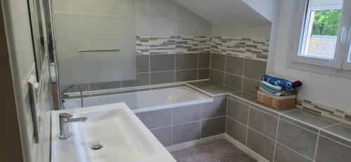 a bathroom with a tub and a sink at Maison chez DANETTE in Thilay