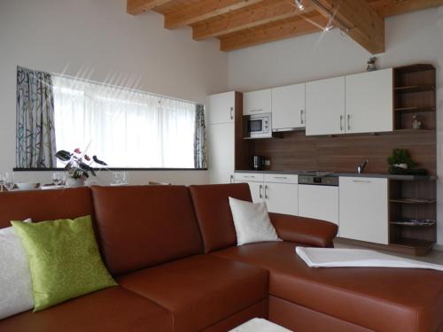 a living room with a brown couch and a kitchen at Haus "Charly" in Nauders
