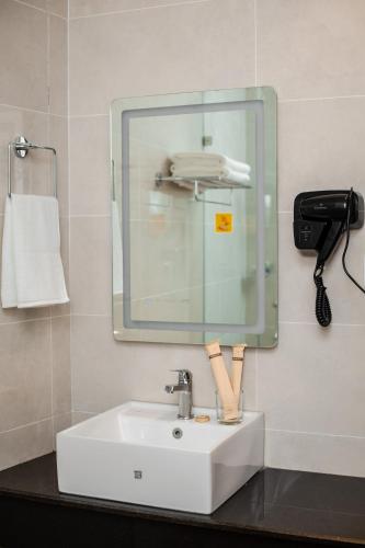 a bathroom with a white sink and a mirror at GermanHomesHotel in Thimi