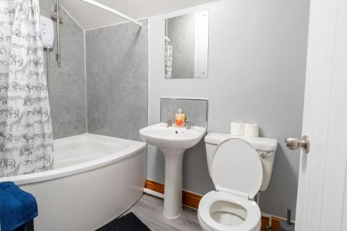 a bathroom with a toilet and a tub and a sink at 3 BD 5 Beds WiFi in Wellingborough