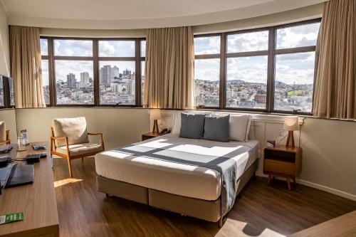 a hotel room with a large bed and windows at Marques Plaza Hotel in Pouso Alegre