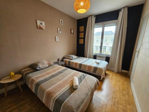 two beds in a room with a window at Quai de la Gare, Appartement étape, 2 chambres, face à la Gare in Châtellerault