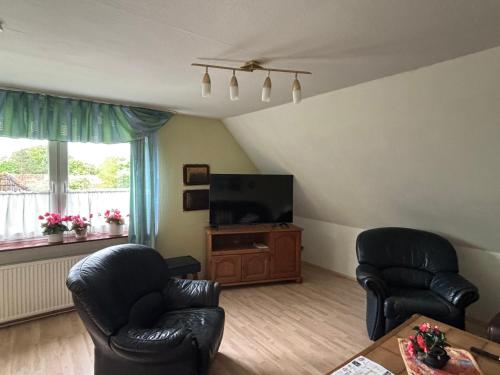 a living room with two chairs and a flat screen tv at Gemütliche Ferien oder Monteurs Wohnung in Wallsbüll