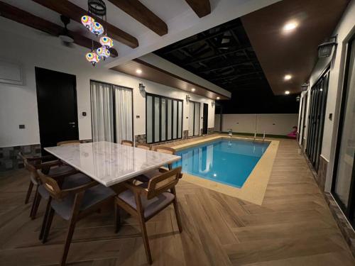 a swimming pool with a table and chairs in a room at Elite Cozy Home 5BR5B, BBQ, Karaoke, Netflix, Near MITC in Ayer Keroh