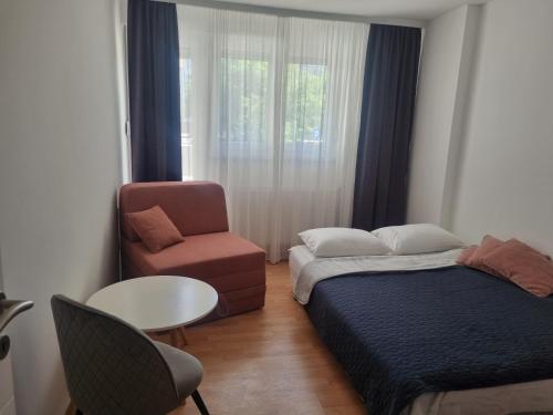 a bedroom with a bed and a chair and a table at Apartman Milica 1 in Doboj